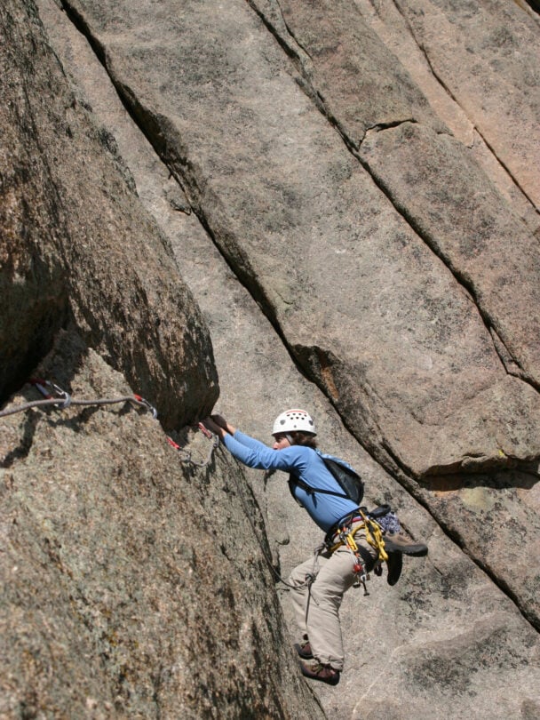 "Female climber makes the traverse from one line to the next on the fourth pitch of Orange Julius - Lumpy Ridge, Rocky Mountain National Park."